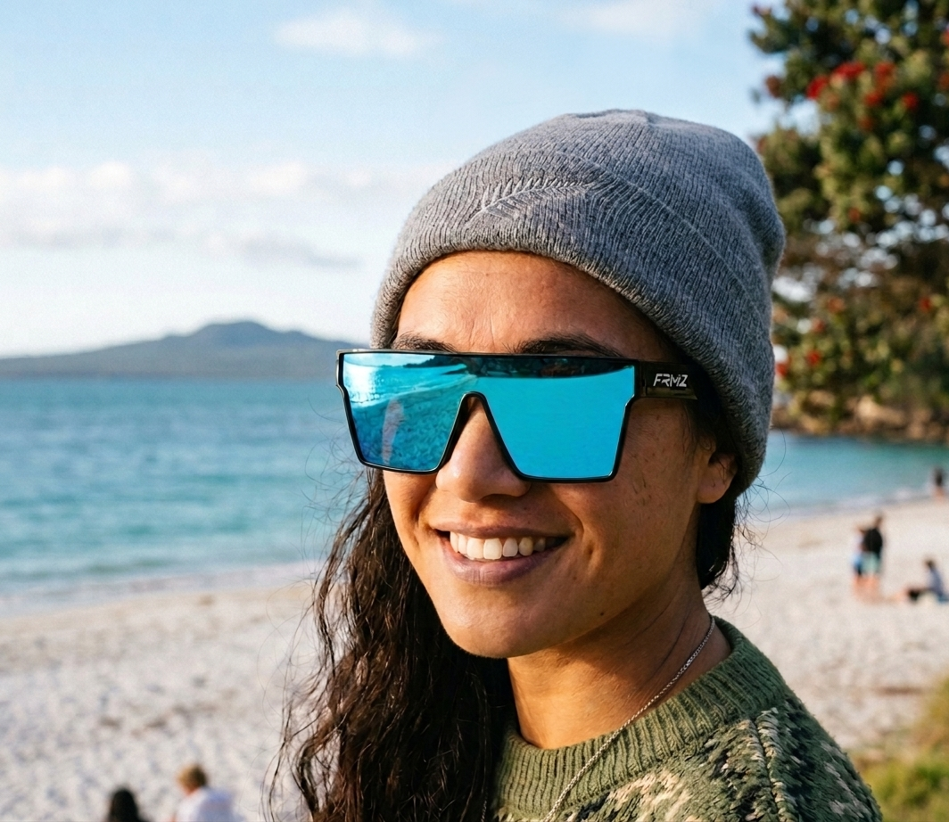 Person wearing FRMZ Eyewear blue mirrored polarized shield sunglasses on a New Zealand beach.
